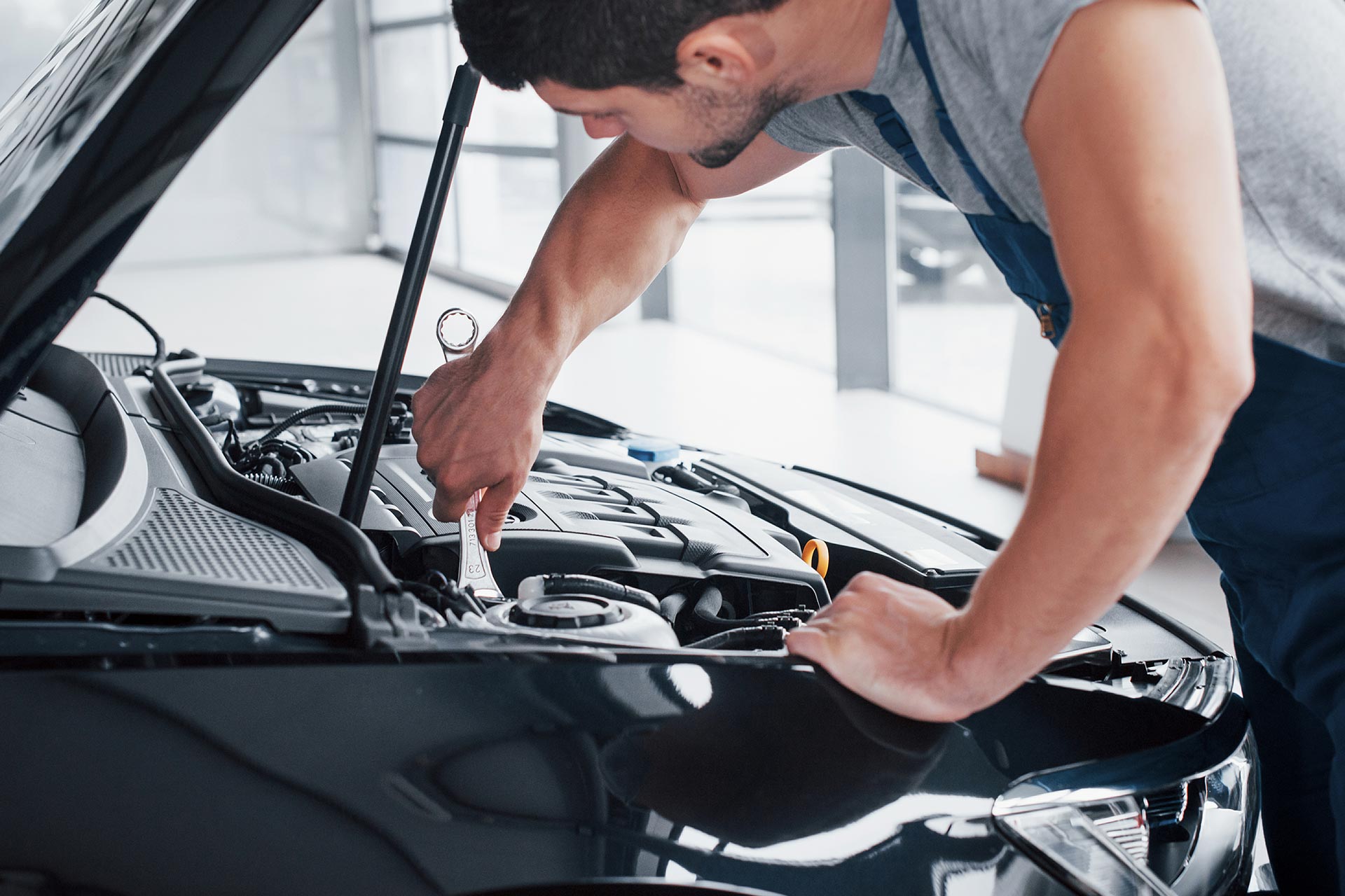 A mechanic fixing a car's engine under the open hood.