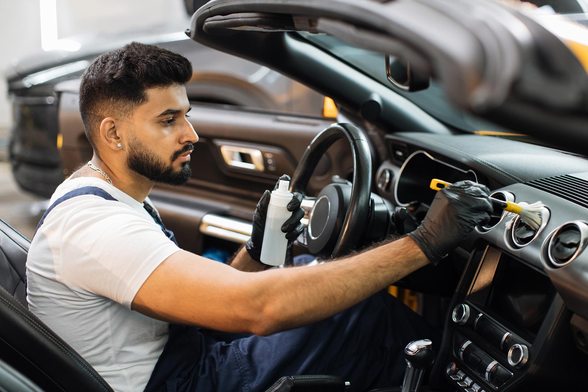 A mechanic diligently repairing a car in a well-equipped garage, surrounded by tools and equipment.