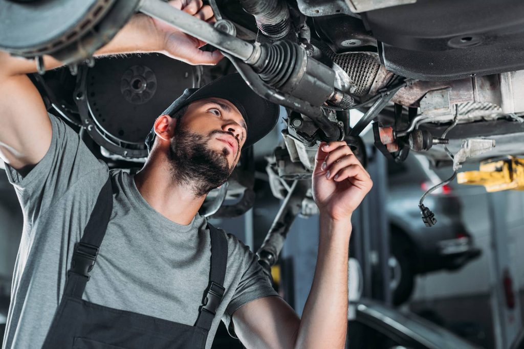 Auto technician working on car in garage.