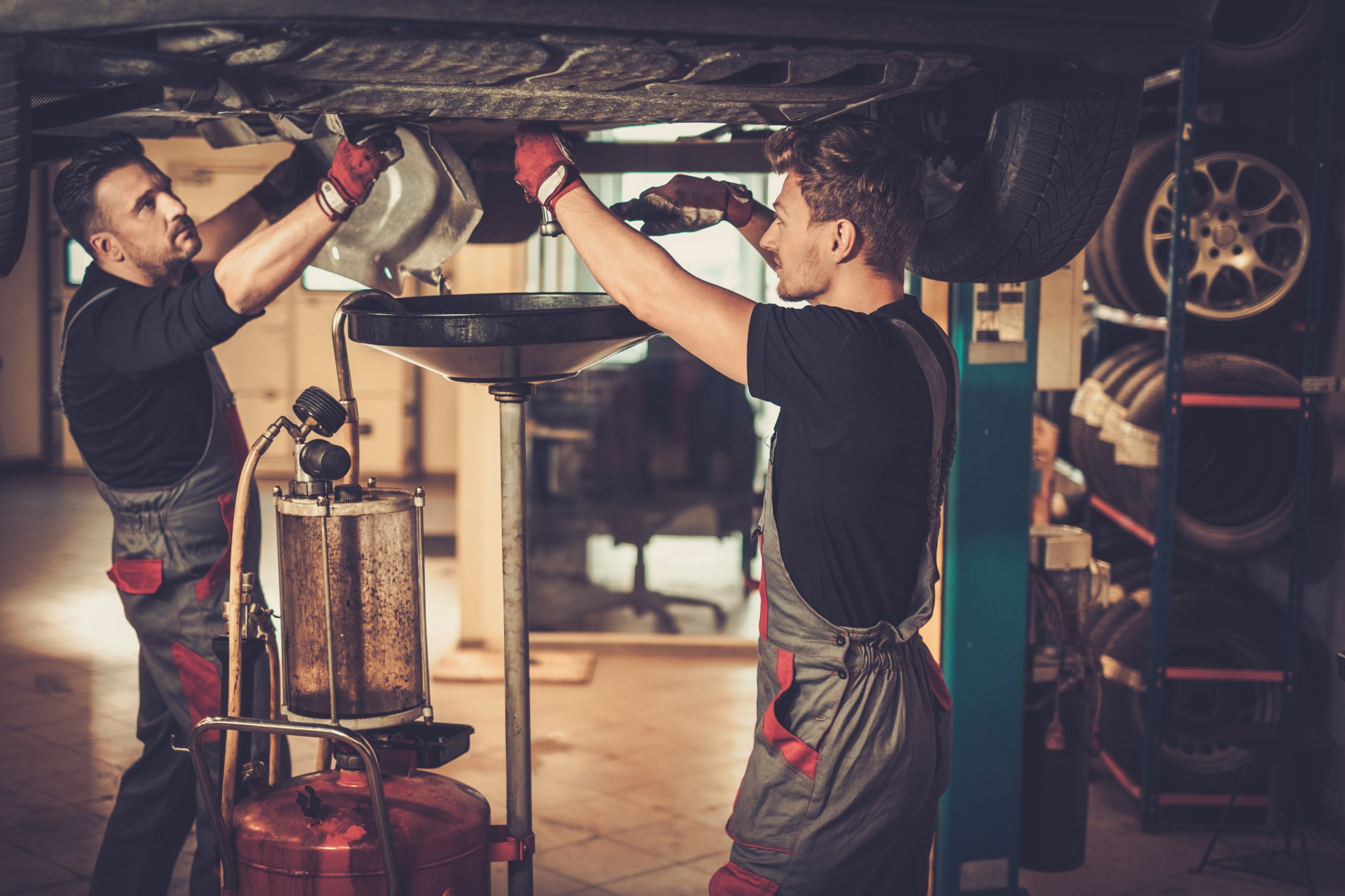 Professional car mechanic changing motor oil in automobile engi