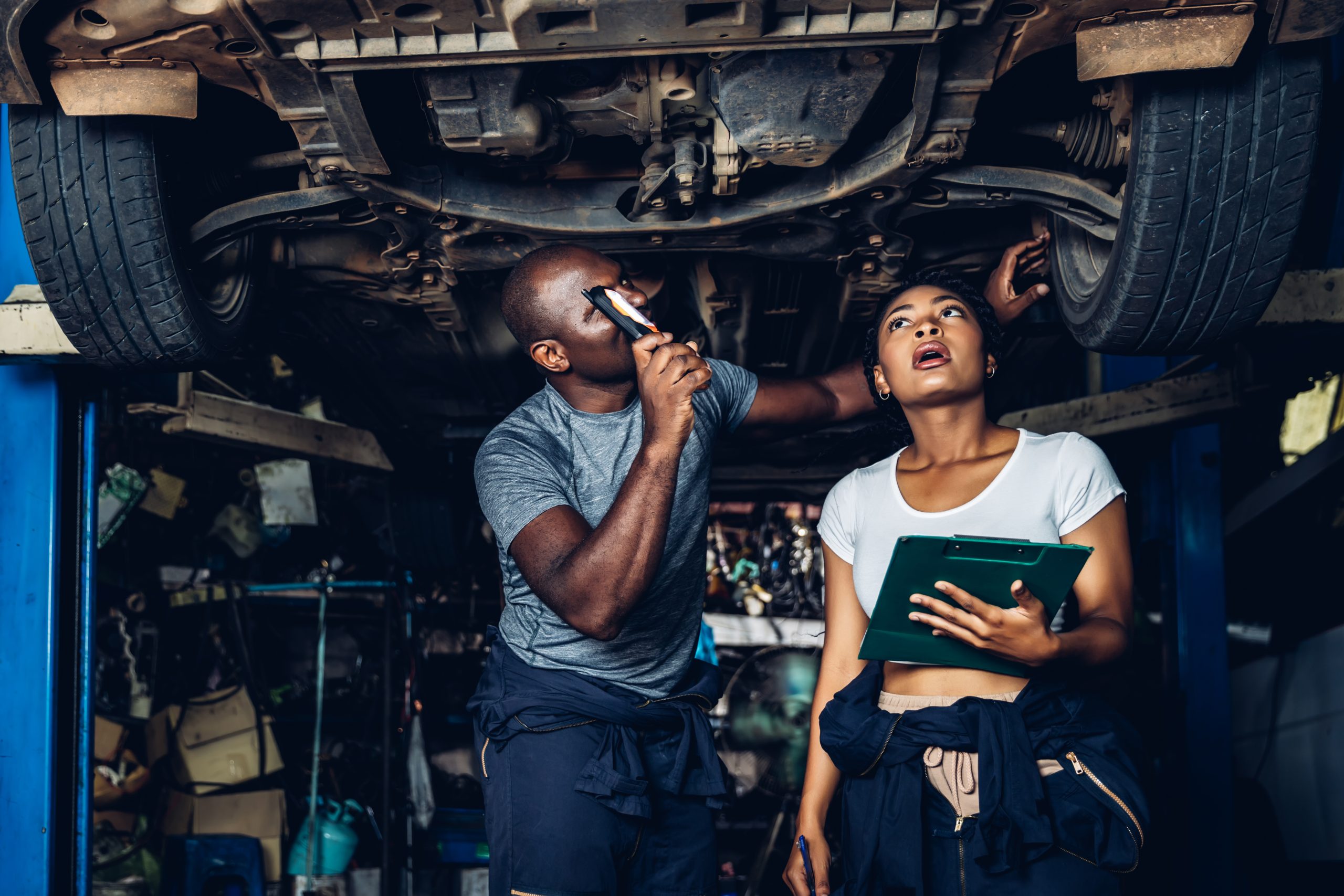 Professional Car Mechanic is Investigating Under a Vehicle on a
